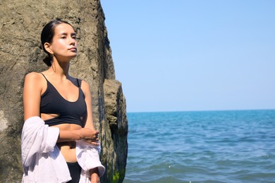 Photo of Beautiful young woman in stylish bikini near sea, space for text