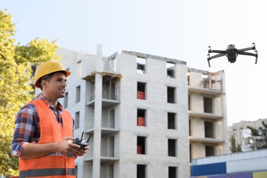 Photo of Builder operating drone with remote control at construction site. Aerial photography