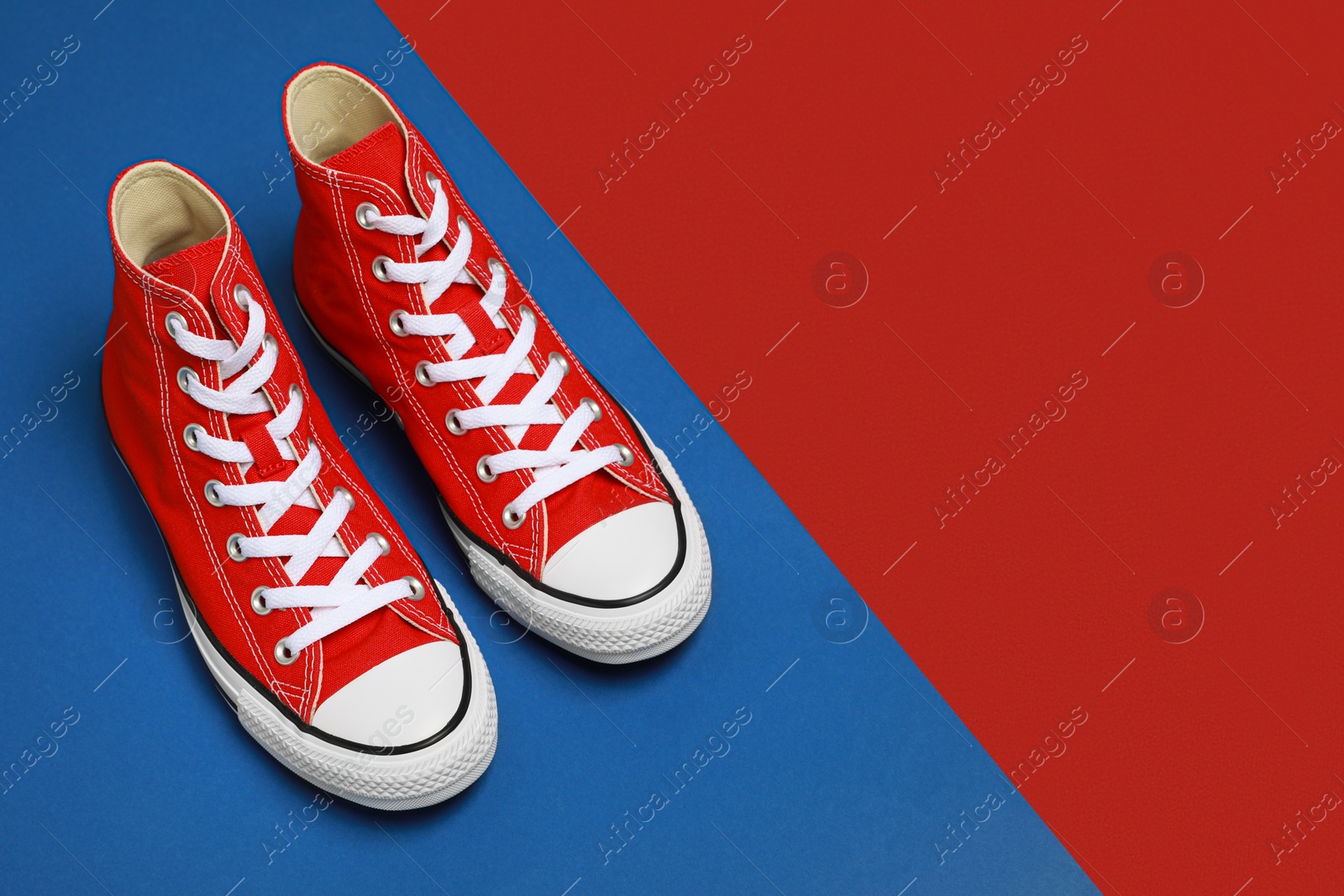 Photo of Pair of new stylish red sneakers on colorful background. Space for text