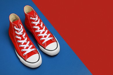 Pair of new stylish red sneakers on colorful background. Space for text