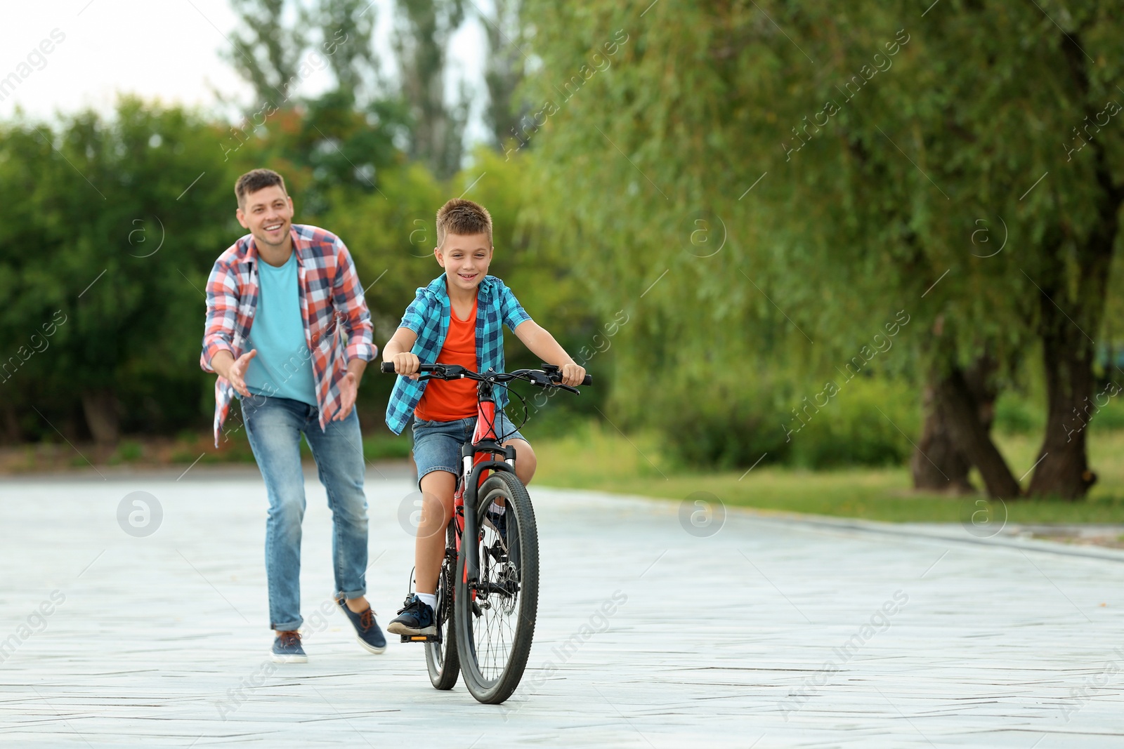 Photo of Dad teaching son to ride bicycle in park