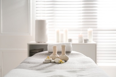 Photo of Herbal bags, orchid flowers and stones on couch in spa salon