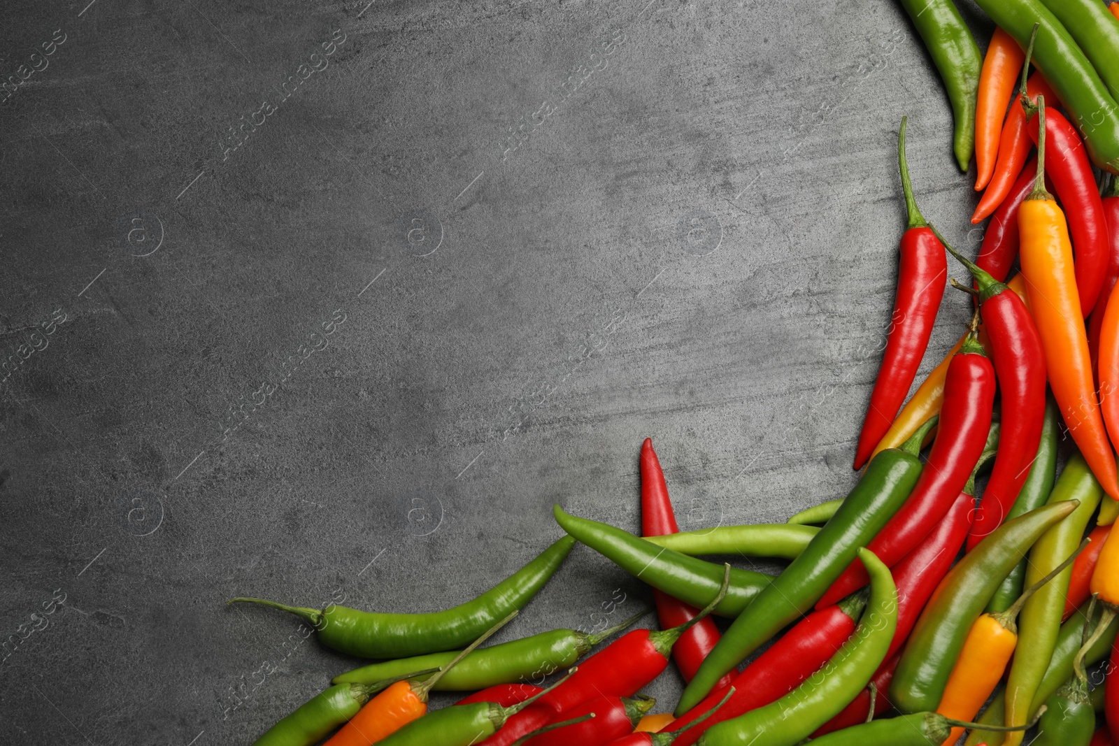 Photo of Different ripe chili peppers grey table, flat lay. Space for text