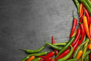 Photo of Different ripe chili peppers grey table, flat lay. Space for text