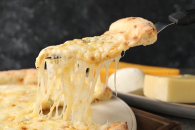 Taking piece of delicious cheese pizza at table, closeup