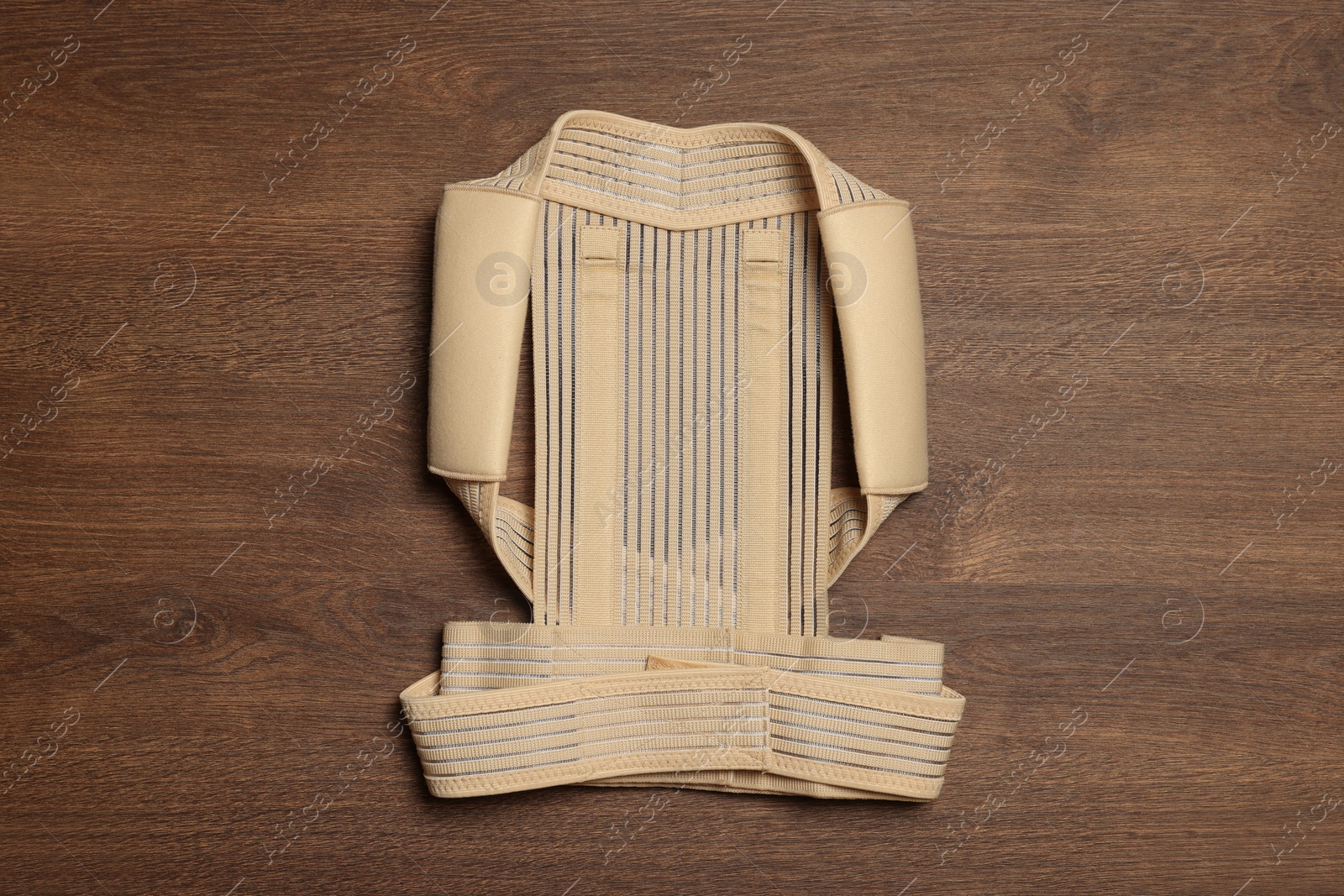 Photo of Beige posture corrector on wooden table, top view