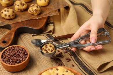 Photo of Woman making delicious chocolate chip cookies at wooden table, closeup