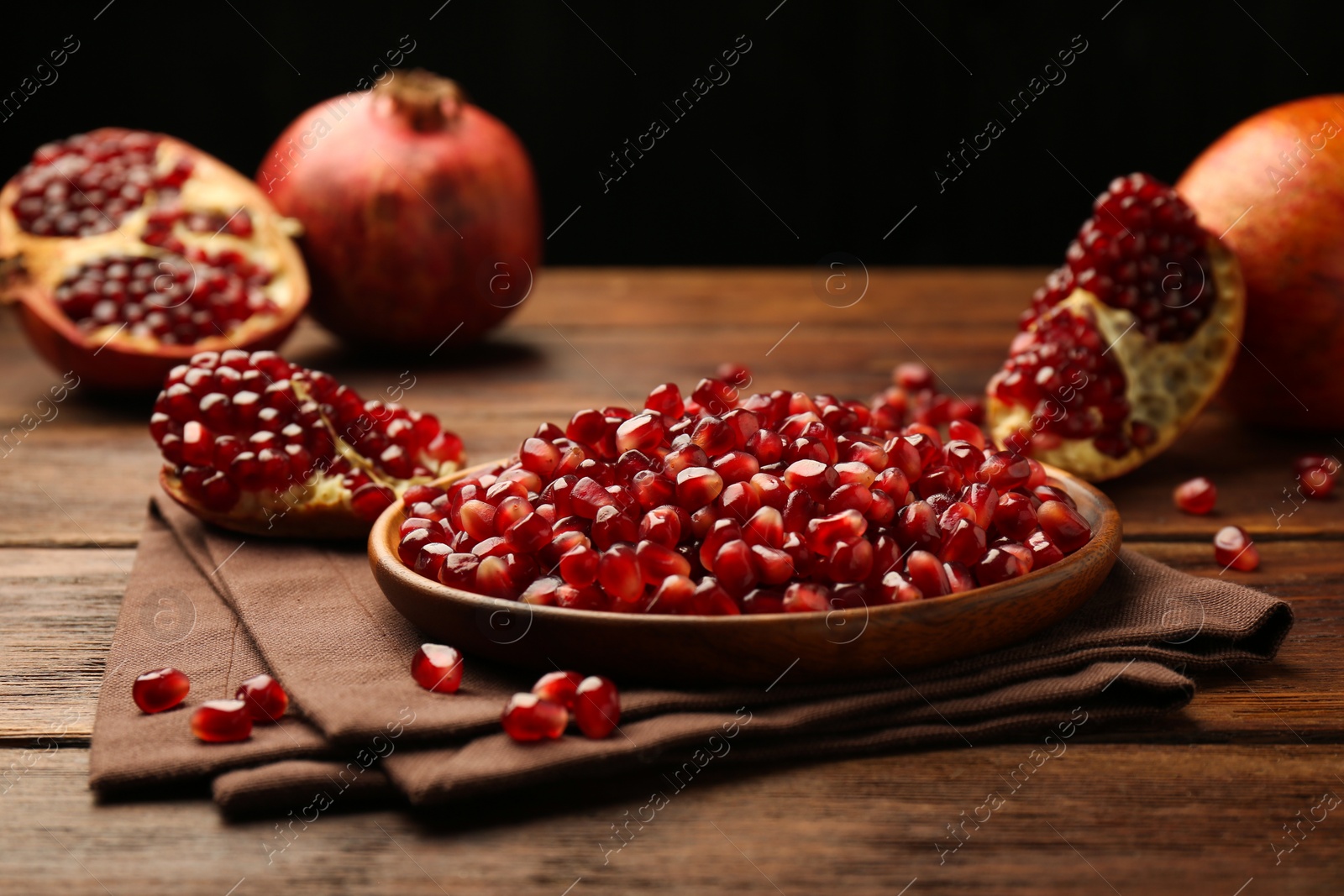 Photo of Ripe juicy pomegranates and grains on wooden table