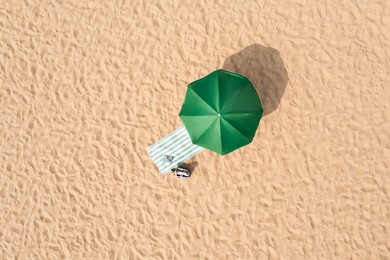 Image of Beach umbrella near towel and other vacationist's stuff on sand, aerial view