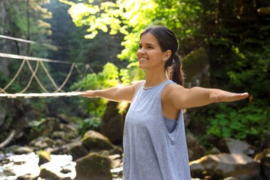 Happy young woman doing morning exercise in mountains