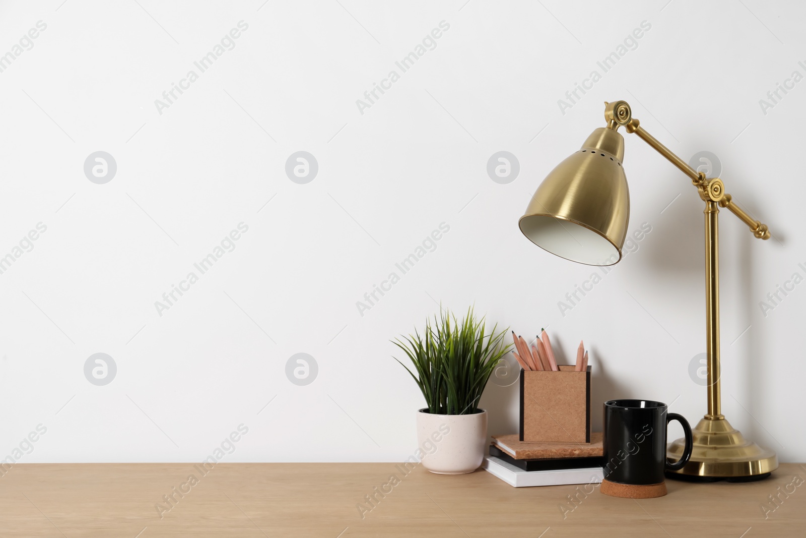 Photo of Comfortable workplace with wooden desk near white wall at home