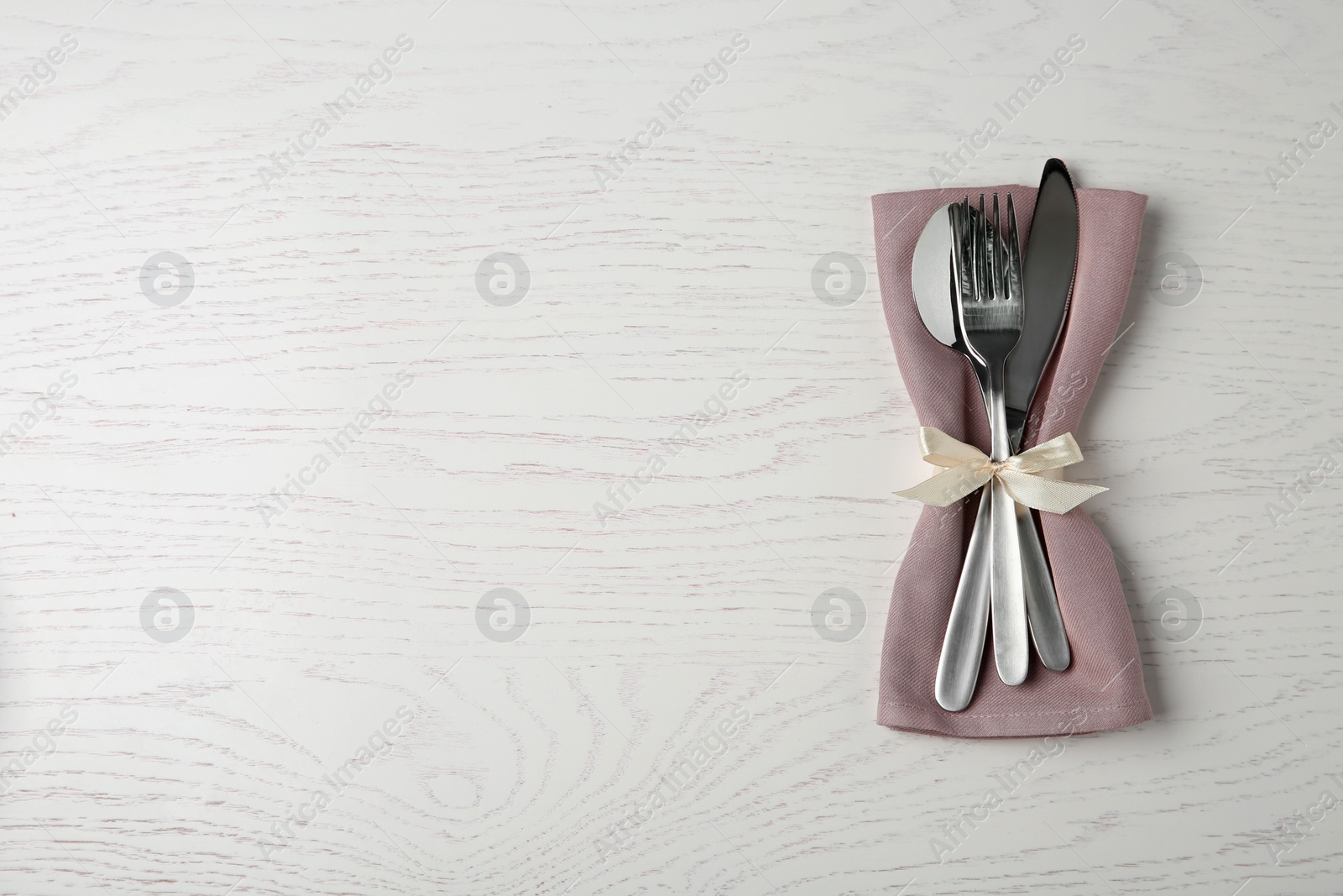 Photo of Cutlery set for festive table on white wooden background, top view. Space for text