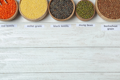 Flat lay composition with different types of legumes and cereals on white wooden table, space for text. Organic grains