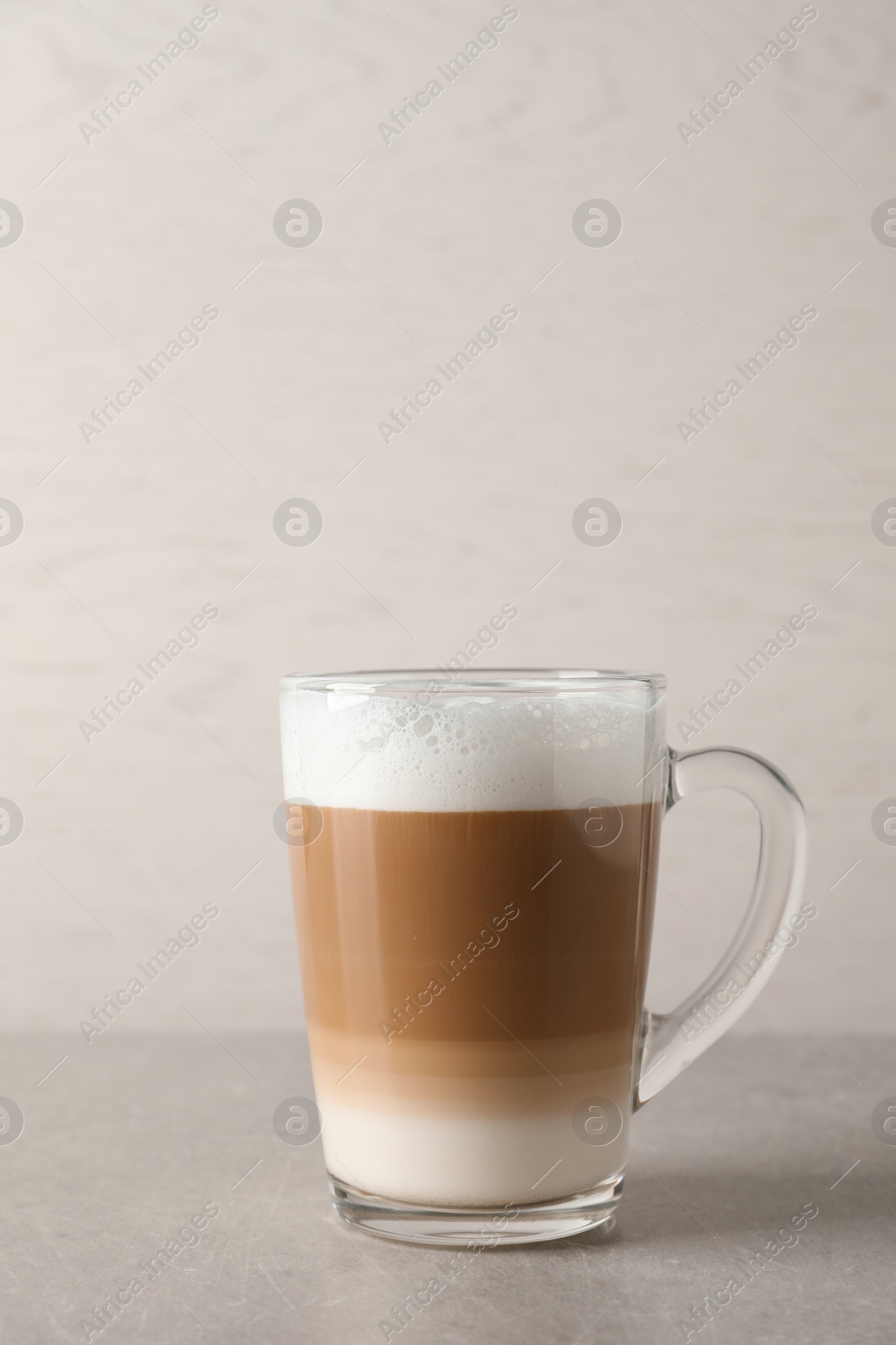 Photo of Hot coffee with milk in glass cup on light table