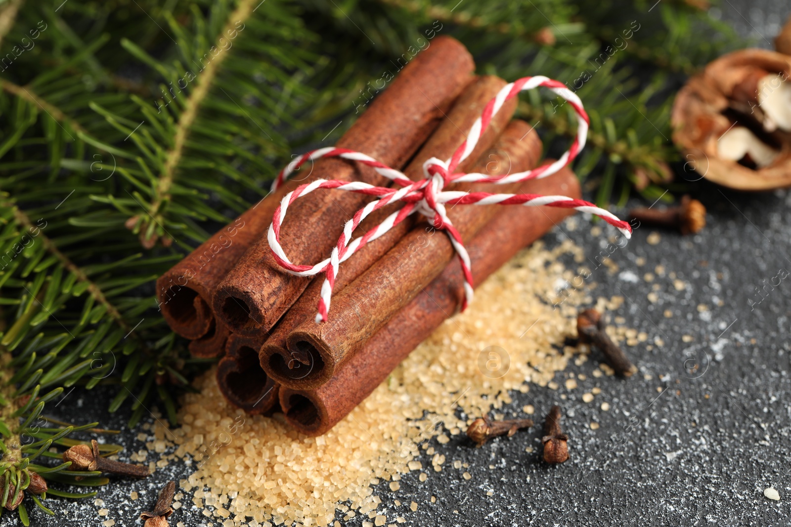 Photo of Different aromatic spices and fir branches on grey textured table, closeup