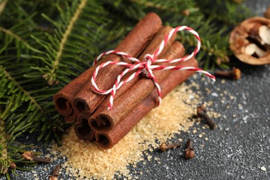 Photo of Different aromatic spices and fir branches on grey textured table, closeup