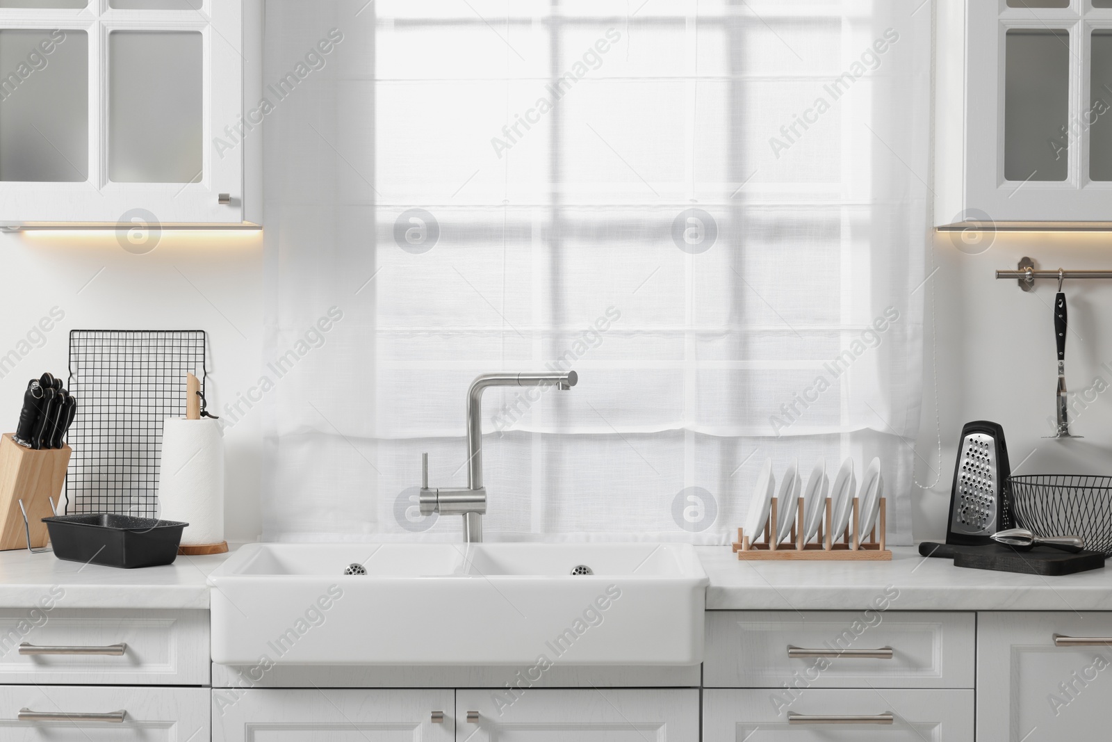 Photo of Set of different utensils near sink on countertop in kitchen