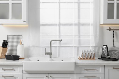 Set of different utensils near sink on countertop in kitchen