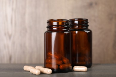 Photo of Gelatin capsules and bottles on wooden table