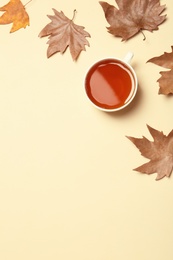 Flat lay composition with hot cozy drink and autumn leaves on color background. Space for text