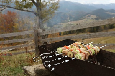 Cooking meat and vegetables on brazier against mountain landscape