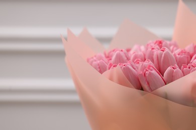 Bouquet of beautiful pink tulips near white wall, closeup. Space for text