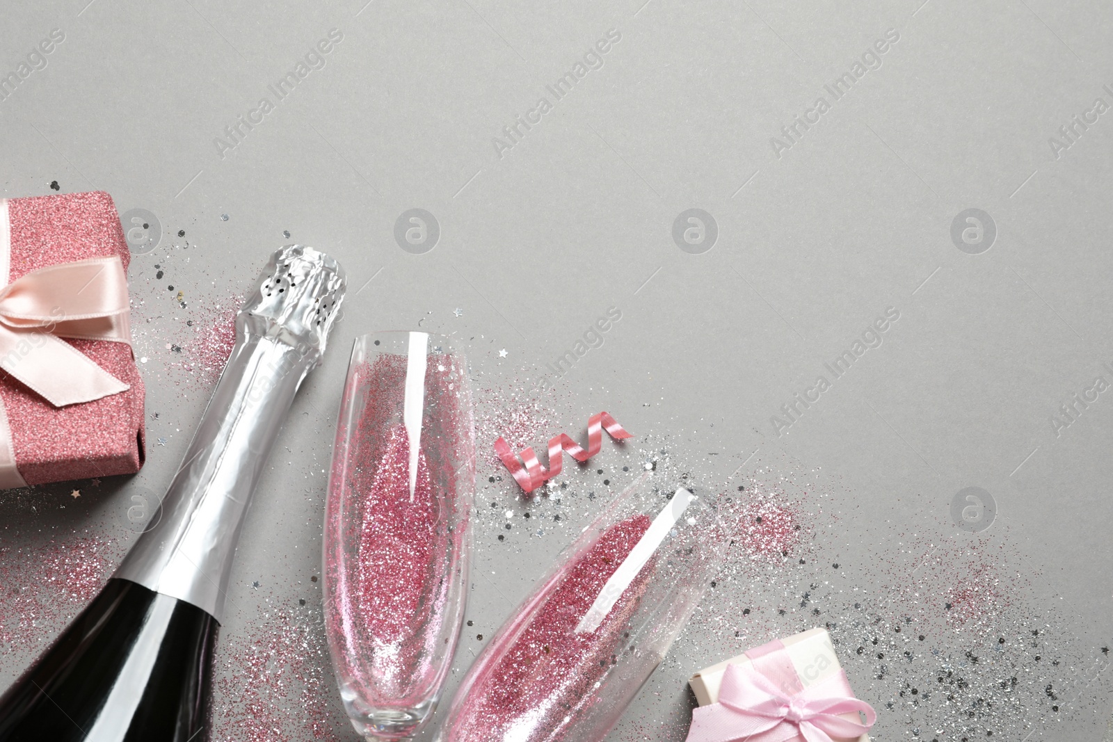 Photo of Flat lay composition with bottle of champagne for celebration on grey background. Space for text