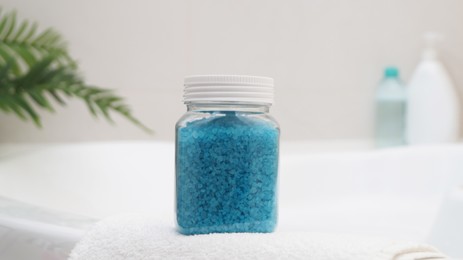 Photo of Jar with sea salt and fluffy towel on bath