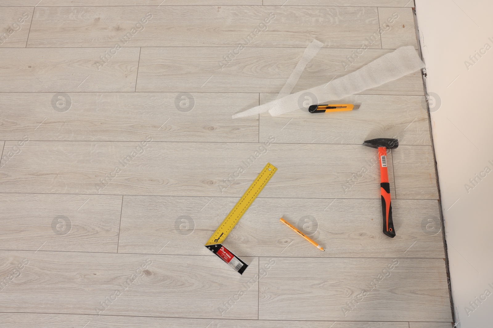 Photo of Hammer, cutter knife, pencil and ruler on laminated floor, flat lay. Space for text
