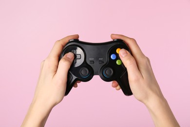 Woman using game controller on pink background, closeup