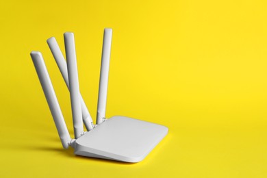 Photo of New white Wi-Fi router on yellow background, space for text