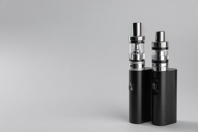 Photo of Two electronic cigarettes on light background, space for text