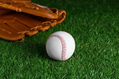 Catcher's mitt and baseball ball on green grass. Sports game