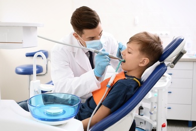 Photo of Professional dentist working with little boy in clinic