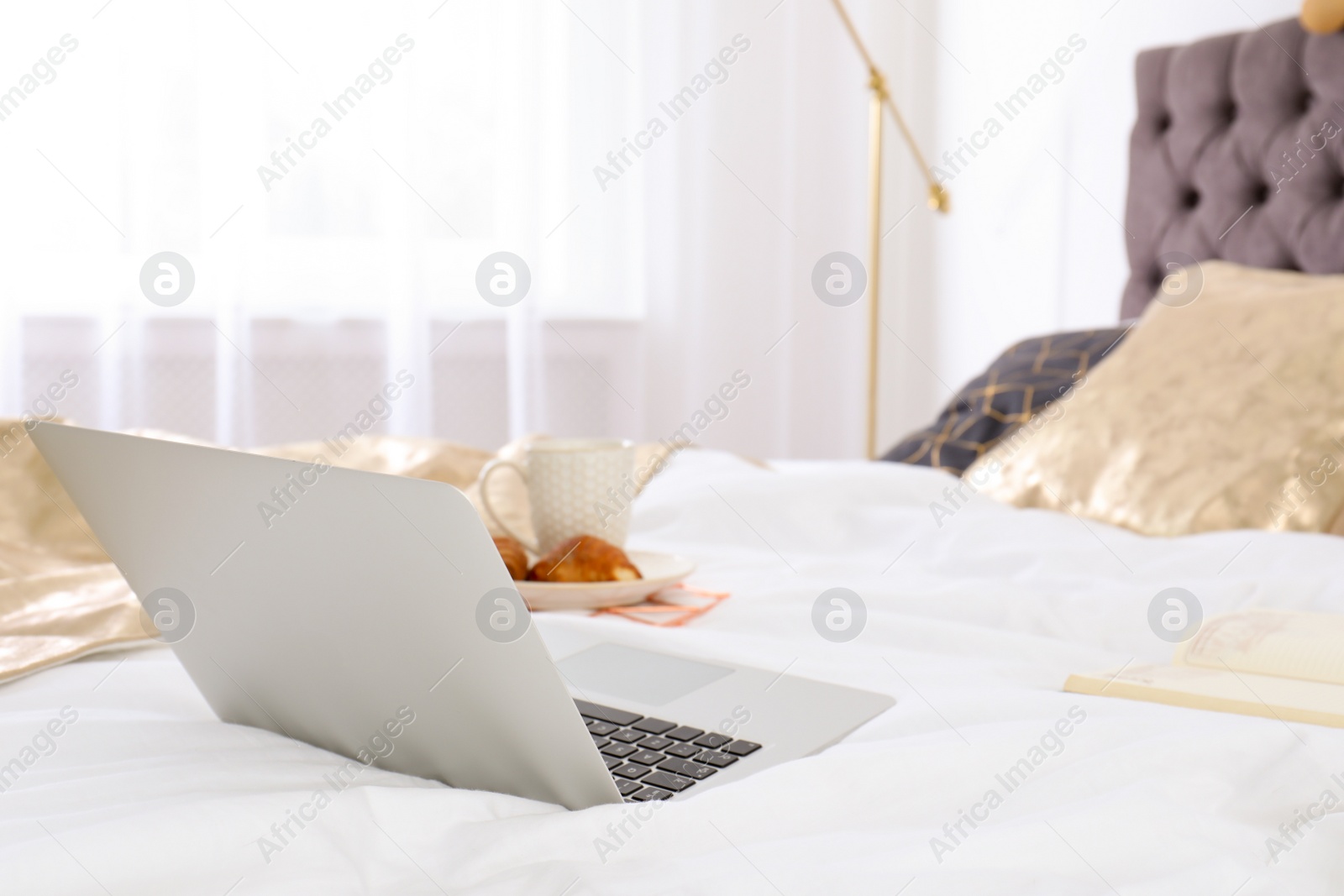 Photo of Laptop and breakfast on bed in stylish room interior