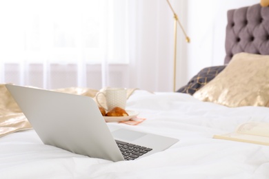 Photo of Laptop and breakfast on bed in stylish room interior