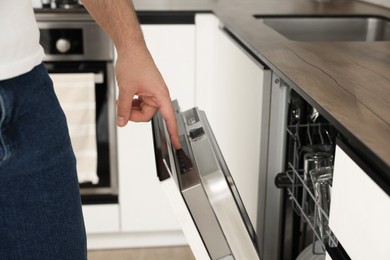 Man pushing button on dishwasher's door indoors, closeup