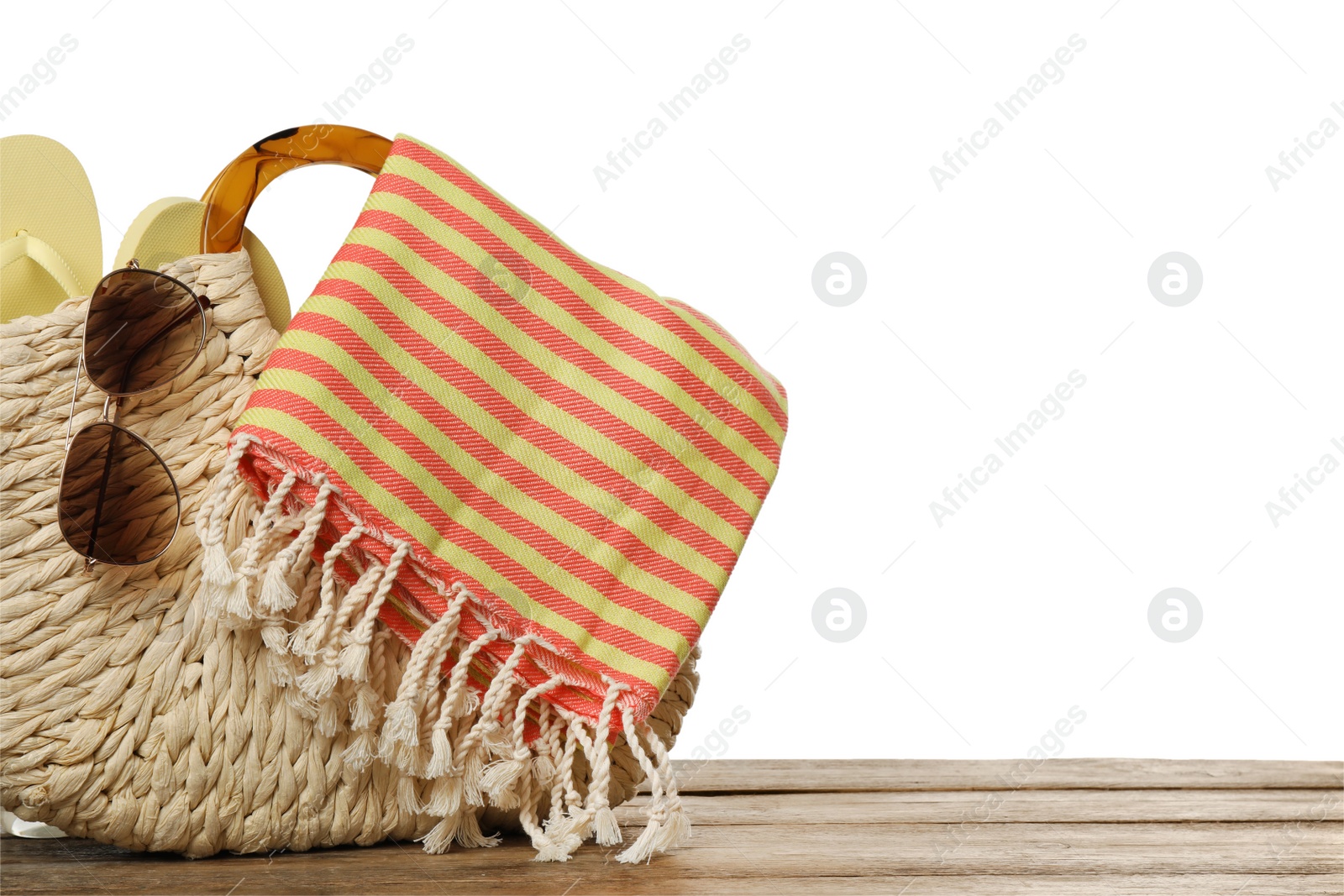 Photo of Beach bag with towel, flip flops and sunglasses on wooden surface against white background. Space for text