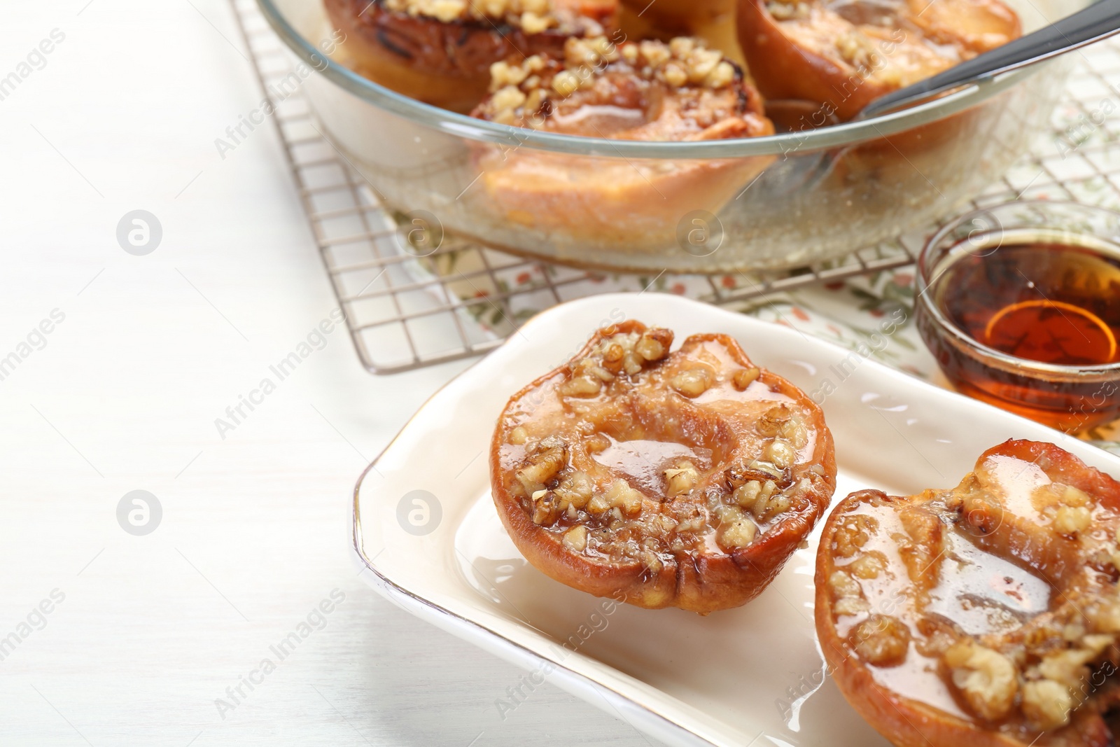 Photo of Delicious quinces baked with honey and walnuts on white table
