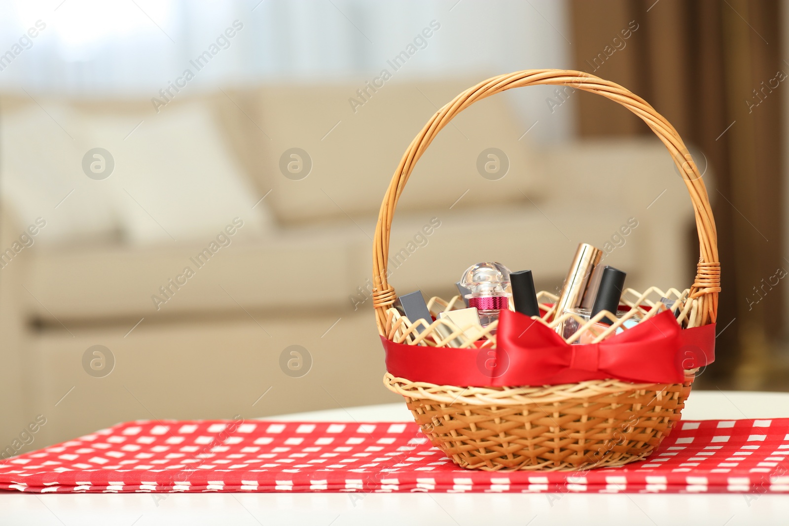 Photo of Wicker basket full of gifts on white table in living room. Space for text