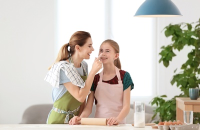 Mother and her daughter making dough at table in kitchen