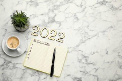 Photo of Making resolutions for 2022 New Year. Flat lay composition with notebook on white marble table
