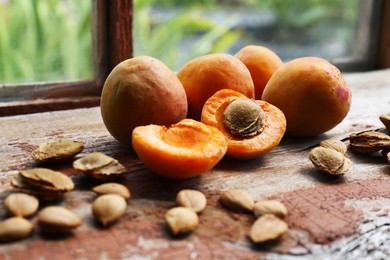 Photo of Delicious ripe apricots with stones on wooden table near window, closeup