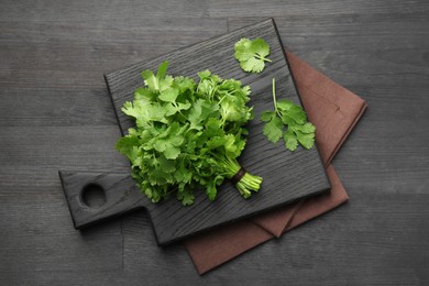 Photo of Bunch of fresh coriander on black wooden table, top view