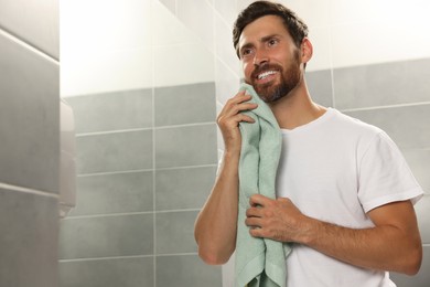 Photo of Handsome man drying his beard in bathroom. Space for text