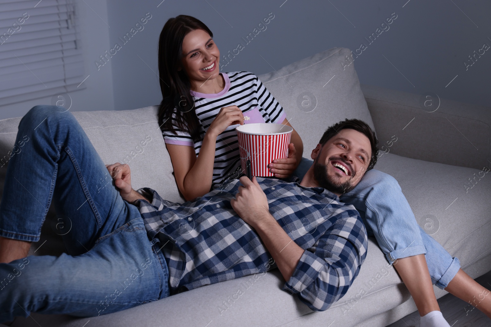 Photo of Happy couple watching comedy via TV at home in evening