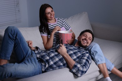 Happy couple watching comedy via TV at home in evening