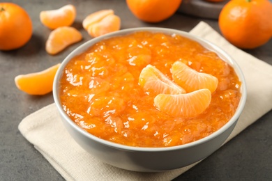 Tasty tangerine jam in bowl on grey table