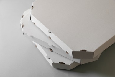 Photo of Stack of empty pizza boxes on grey background, closeup