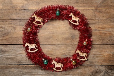 Frame of bright tinsel and Christmas decor on wooden background, top view. Space for text